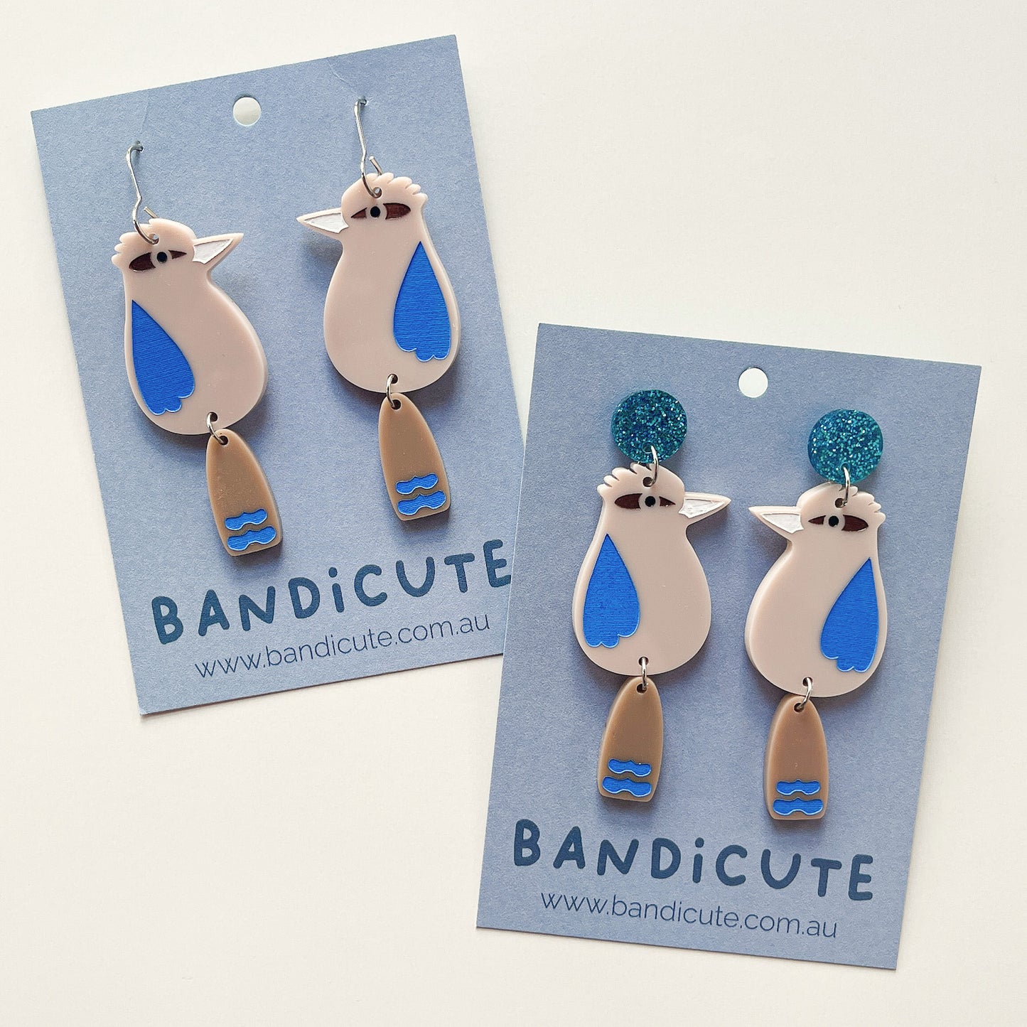 Mini kookaburra dangle earrings. Beige with brown tails, blue painted features.