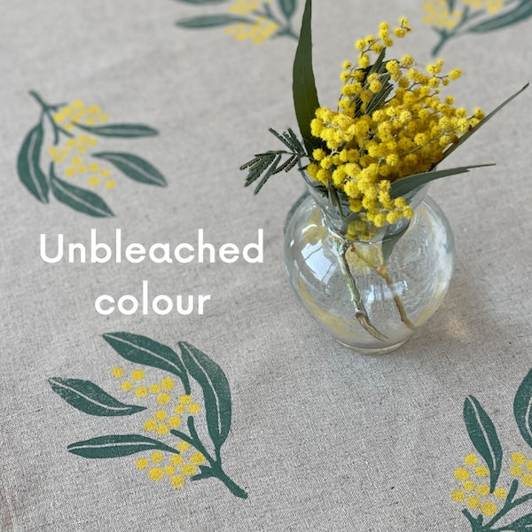 Close up of wattle table runner in unbleached colour with glass vase with wattle flower