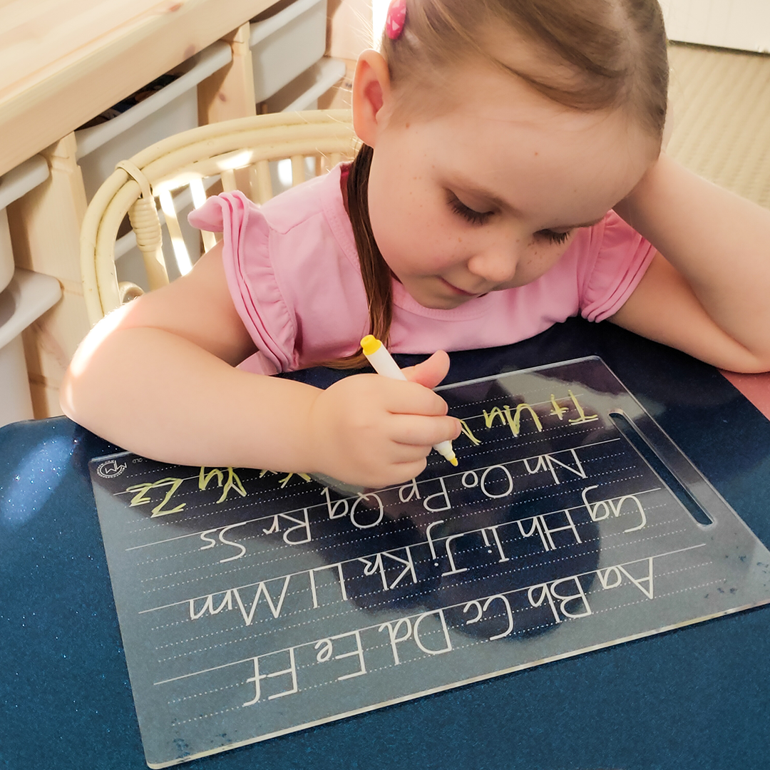 Girl with hand on head while writing with Alphabet Tracing Board