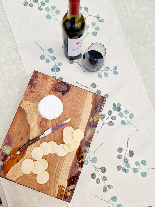 Top down view of gum leaf table runner with cheese, biscuits and wine bottle and glass